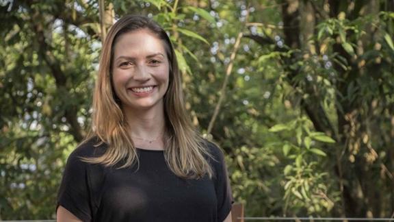 Maria Cristina de Almeida Silva smiling in front of a background of forest.