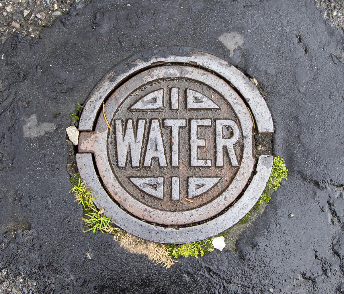 Round, metal, street-level utility cover embossed with the word water 