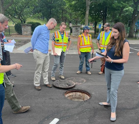 People surrounding an open stormwater drain. 