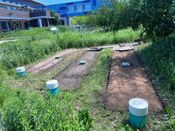 Grassy area with three rectangular bare-ground areas, each with a stand pipe.