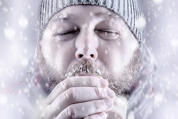 Man with knit hat holding his hands, looking very cold